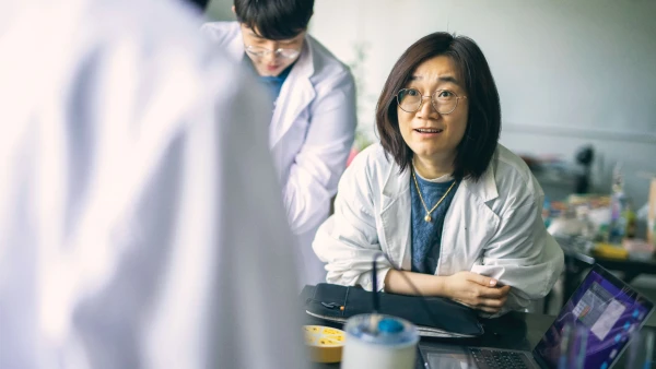 students in lab coats inside international school of qingdao high school learning science