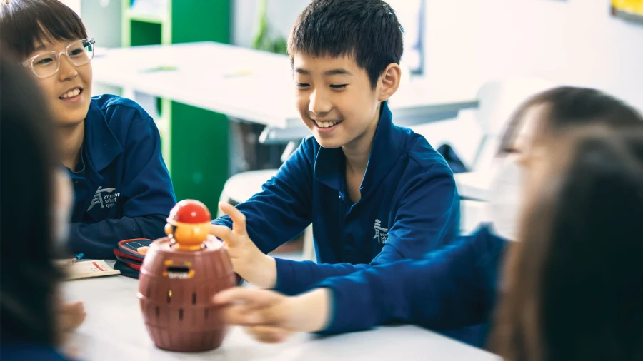 students playing a game in a classroom at international school of qingdao middle school learning teamwork