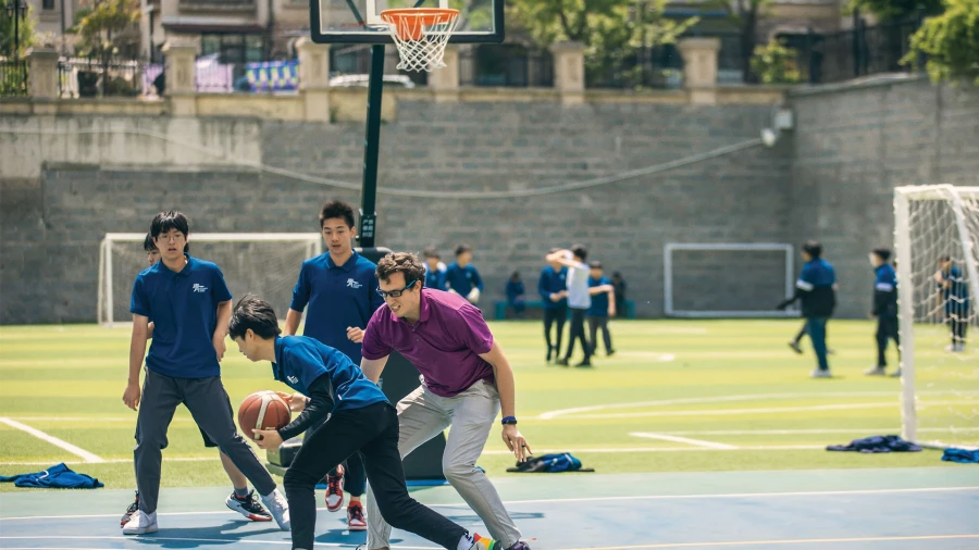four boys playing basketball together international school of qingdao cost and fees