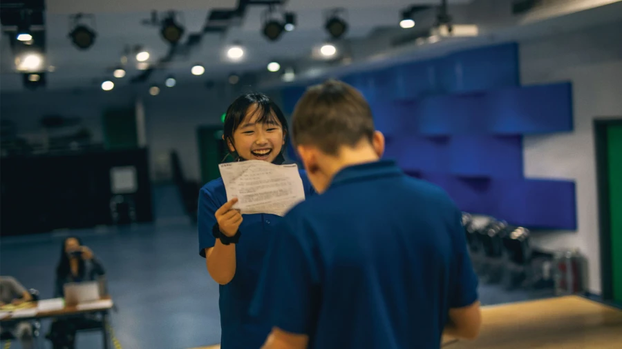 two students on stage at international school of qingdao news and events