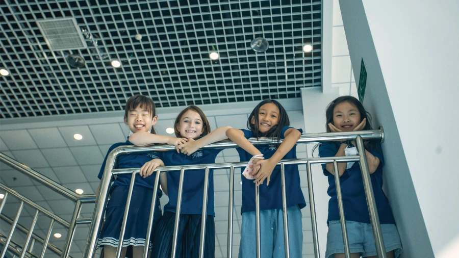 four young female students looking over the railing at international school of qingdao
