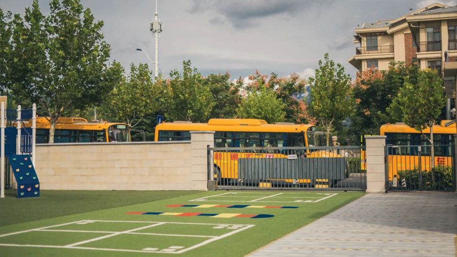 yellow school buses lined up outside the gate of the international school of qingdao